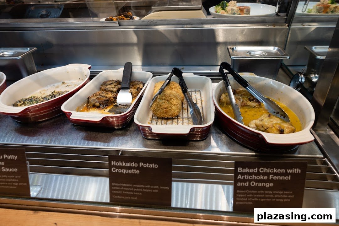 A display of hot prepared dishes including Hokkaido Potato Croquette and Baked Chicken at MUJI.