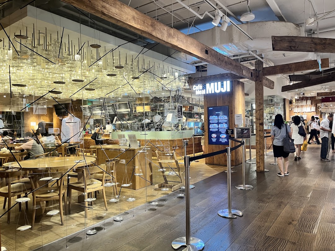 View of the inviting entrance to Café & Meal MUJI, showcasing its natural wood interior and dining area.