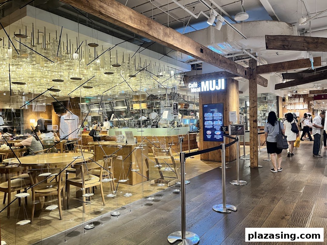 View of the inviting entrance to Café & Meal MUJI, showcasing its natural wood interior and dining area.