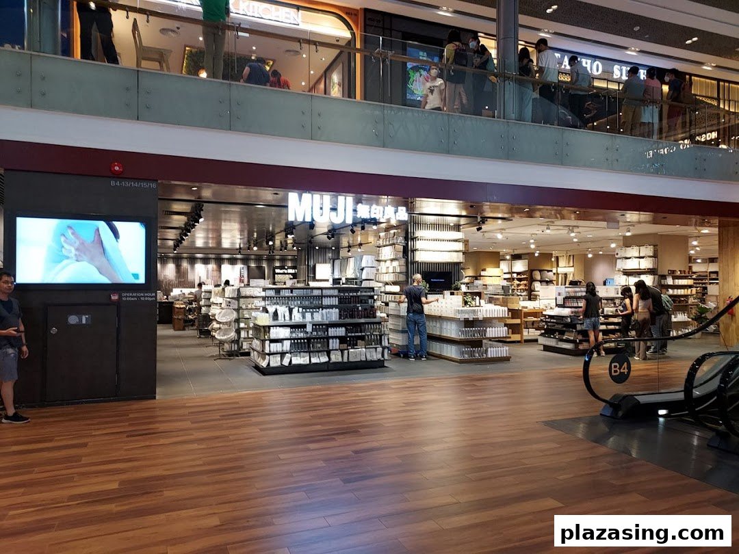 View of MUJI store entrance with interior displays, customers, and a digital screen in a shopping mall.