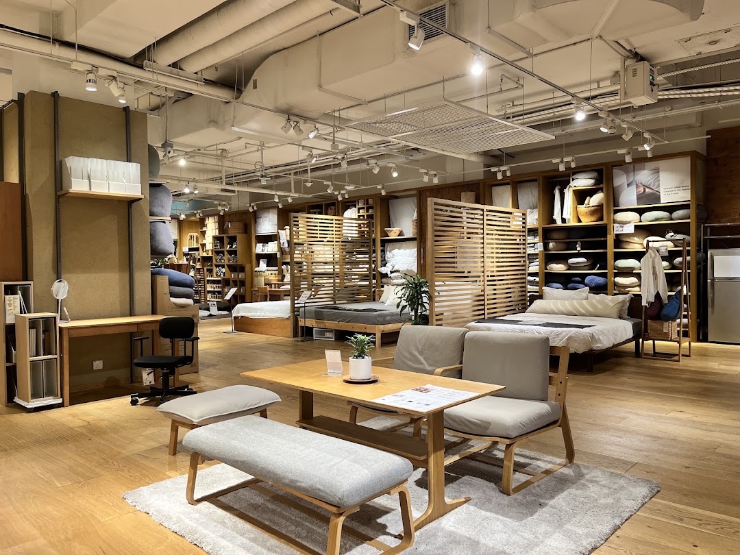 An interior view of MUJI showcasing minimalist furniture, bedding, and home essentials in a warm, inviting setting.
