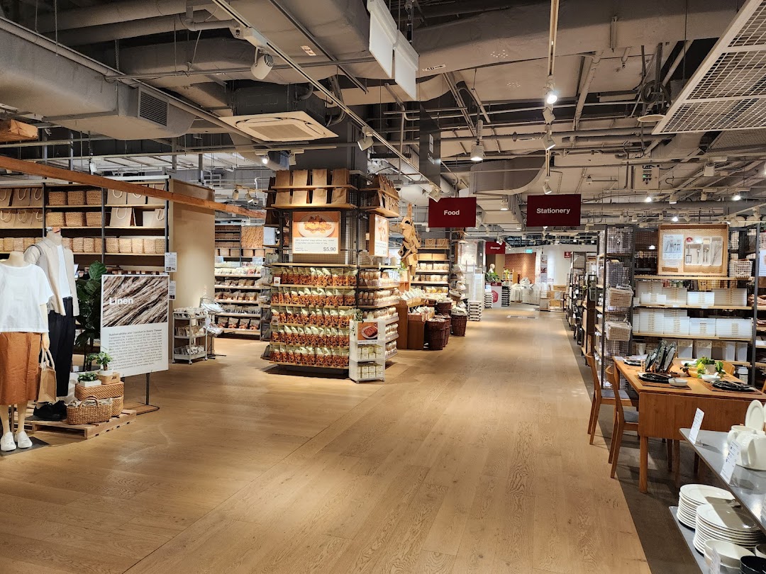A wide interior view of MUJI Plaza Singapura, showcasing various lifestyle products, food, and stationery sections.