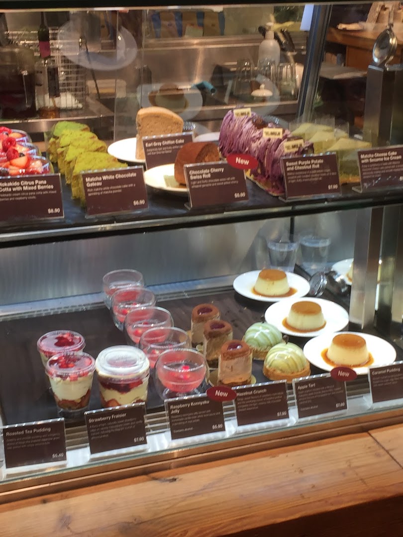 A vibrant display case showcasing a variety of delicious cakes, puddings, and desserts at MUJI Plaza Singapura.