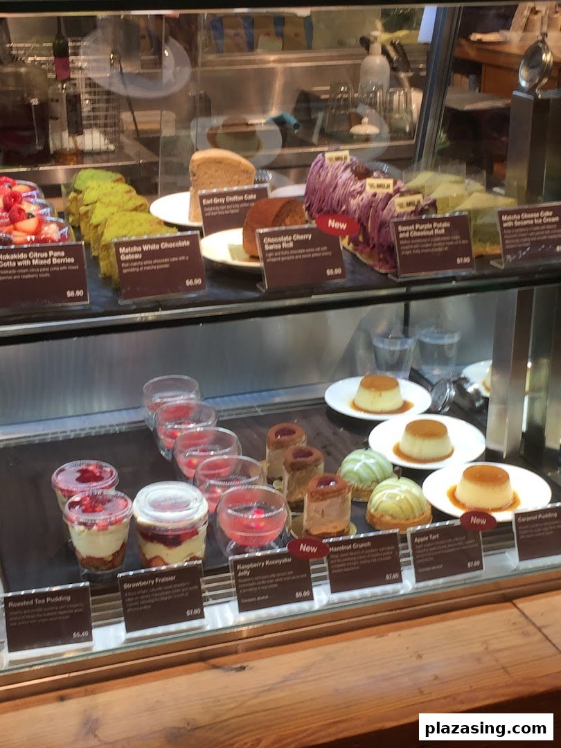 A vibrant display case showcasing a variety of delicious cakes, puddings, and desserts at MUJI Plaza Singapura.