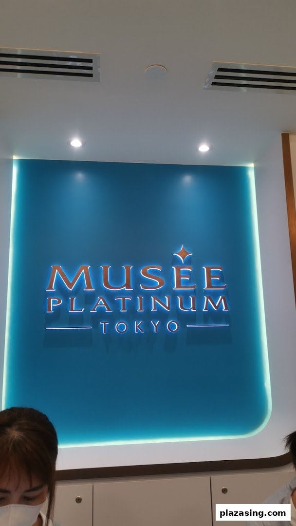 The illuminated Musee Platinum Tokyo logo on a vibrant blue wall inside the shop.