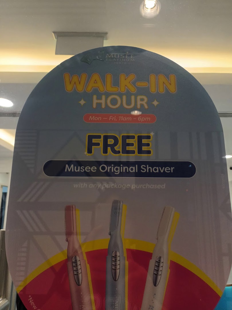 A promotional sign for Musee Platinum Tokyo advertising a 'Walk-In Hour' with a free shaver upon package purchase.