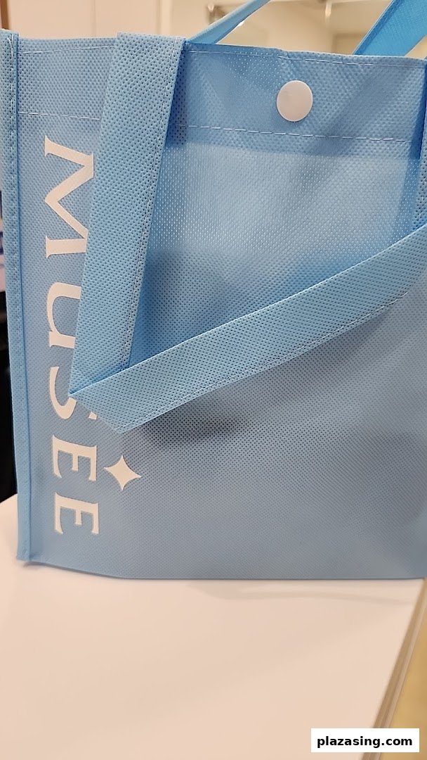 A light blue reusable bag with 'MUSEE' branding and a star-like logo.