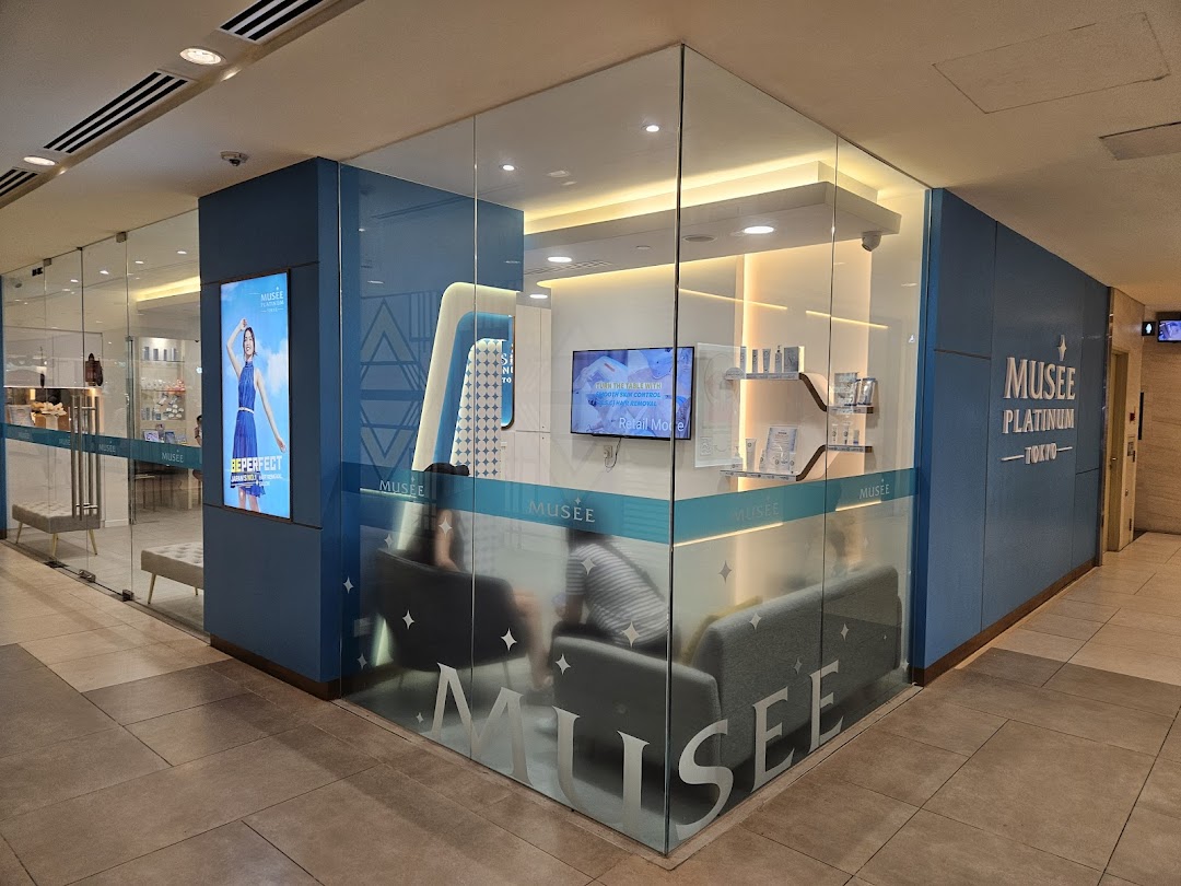 The modern glass and blue exterior of Musee Platinum Tokyo, a beauty and wellness salon.