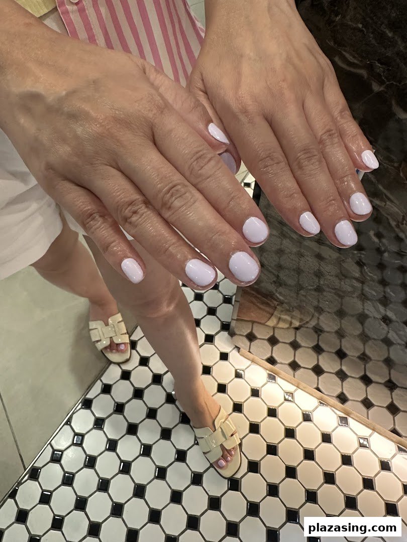 Close-up of hands and feet showcasing freshly painted light purple nails on a stylish tiled floor.