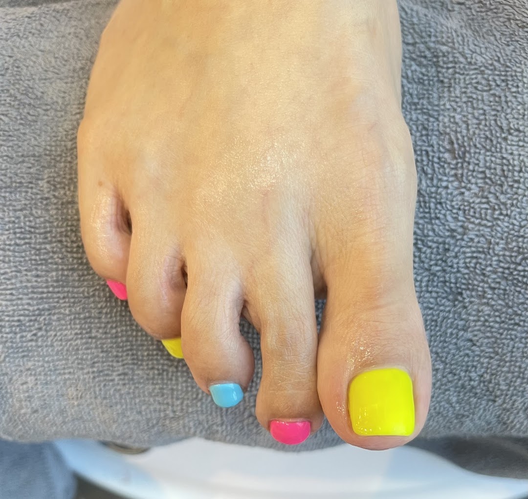 A close-up of a foot showcasing brightly painted toenails in vibrant, multi-colored polish.