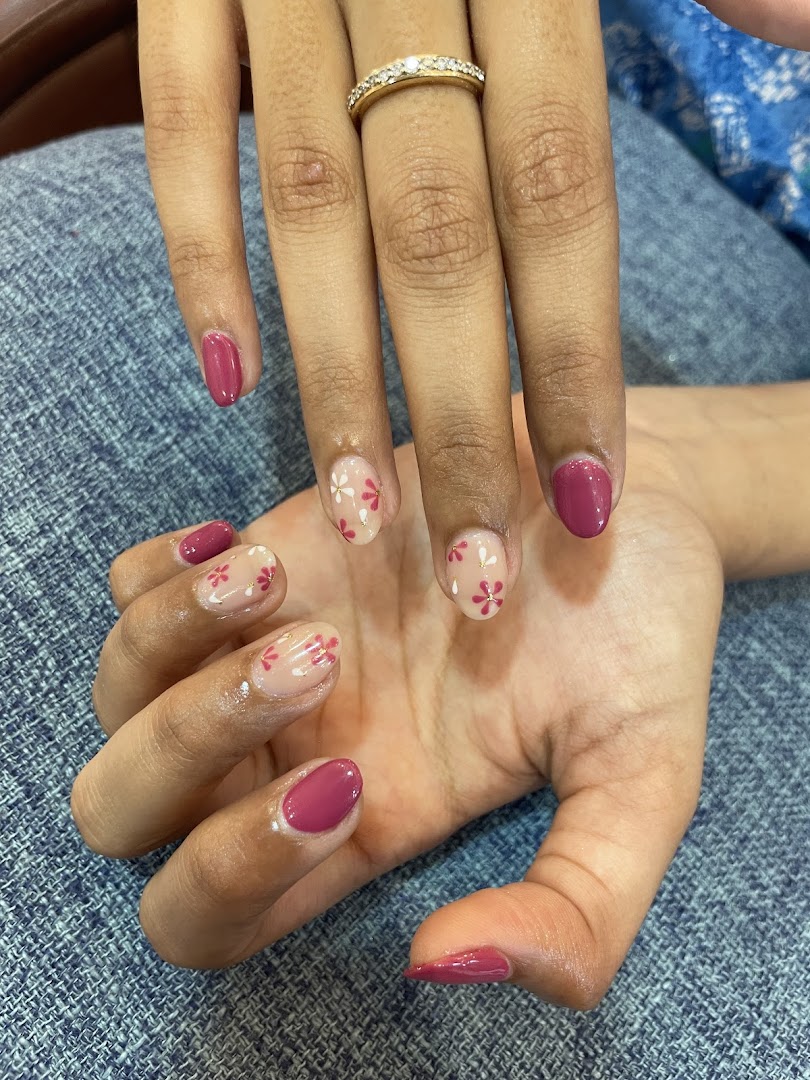 Close-up of hands showcasing a fresh manicure with pink polish and delicate floral nail art.