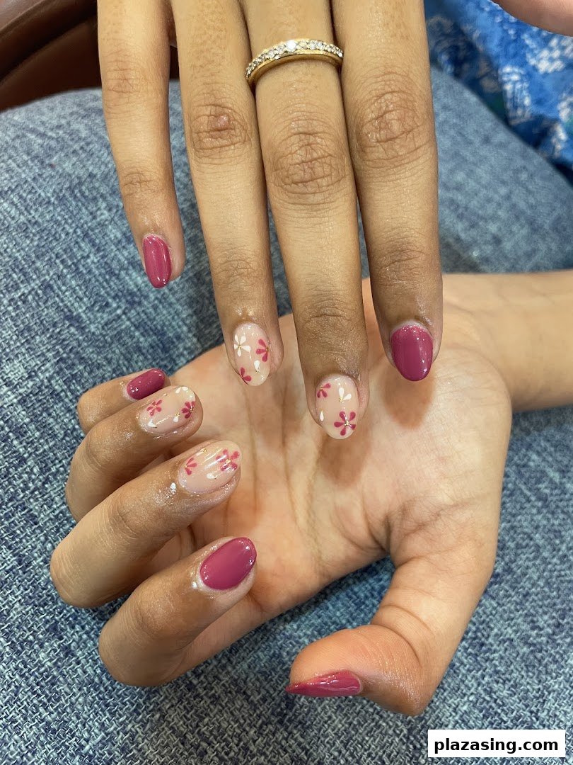 Close-up of hands showcasing a fresh manicure with pink polish and delicate floral nail art.