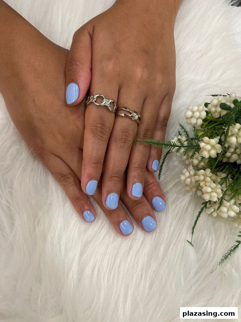 Hands with fresh light blue nail polish, showcasing a perfect manicure on a soft white background.
