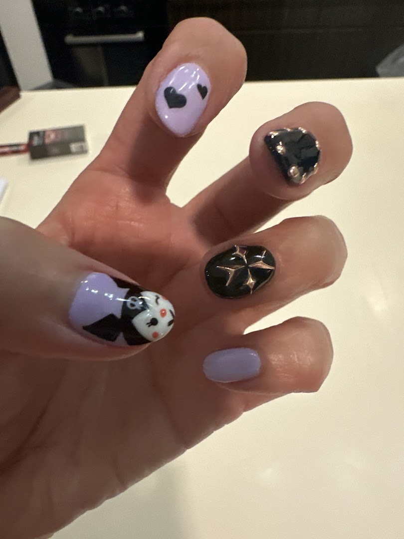 A hand showcasing creative nail art with lavender, black, and white designs, including hearts and a character.