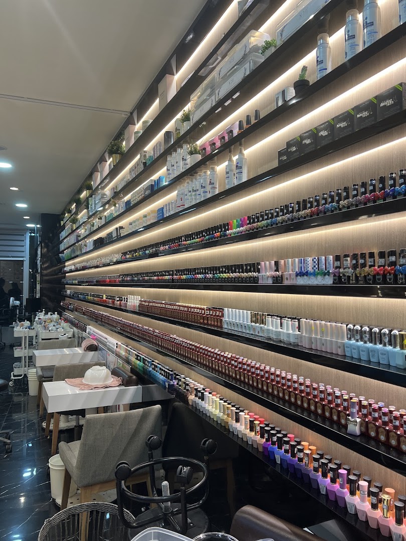A vibrant display of nail polish colors and beauty products lining the illuminated walls of a modern nail spa.