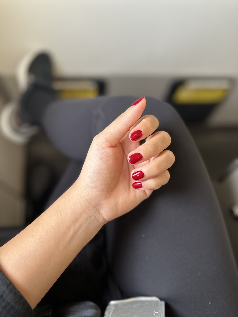 A close-up of a hand with vibrant red nail polish, showcasing a freshly done manicure.