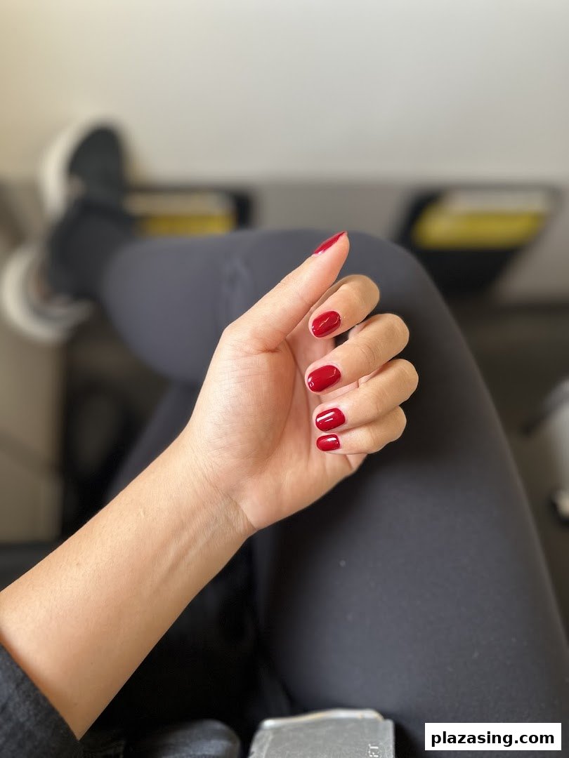 A close-up of a hand with vibrant red nail polish, showcasing a freshly done manicure.