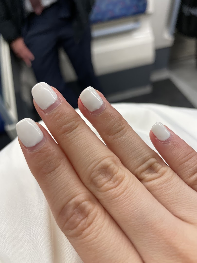 A close-up of a hand showcasing freshly done white nails, possibly after a visit to the nail spa.