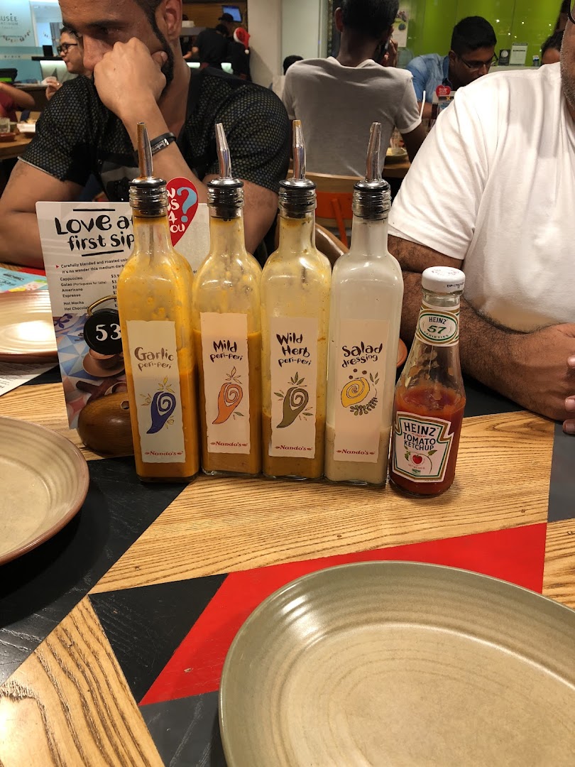 A Nando's table featuring a selection of PERi-PERi sauces and Heinz ketchup.