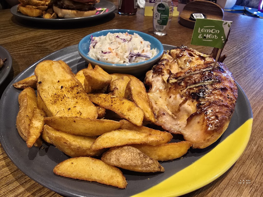 A plate of Nando's flame-grilled chicken with potato wedges and coleslaw.