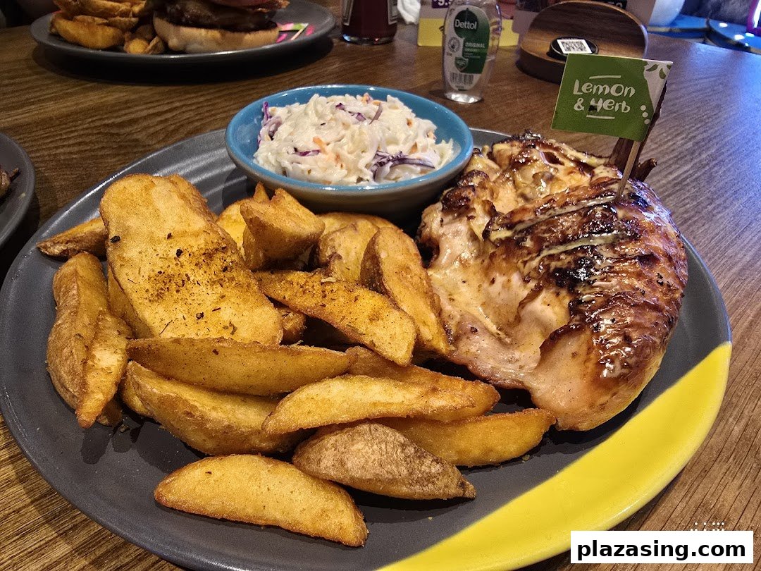 A plate of Nando's flame-grilled chicken with potato wedges and coleslaw.