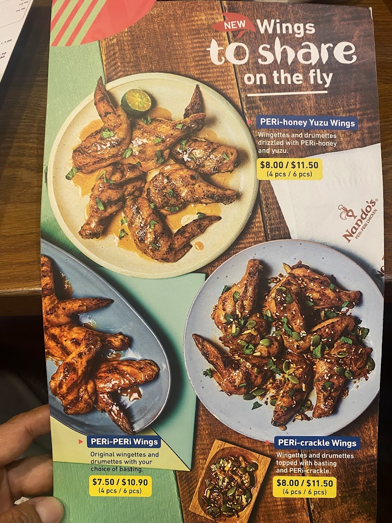 A close-up of a Nando's menu showcasing various flame-grilled chicken wing options.