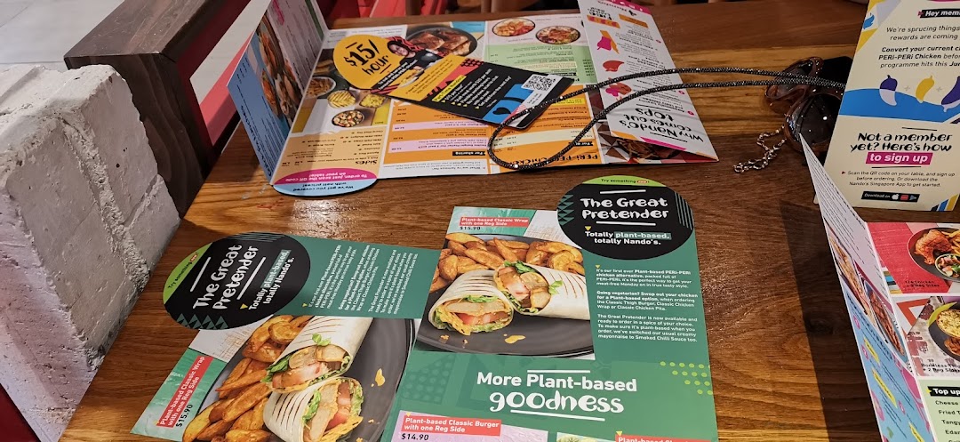 A wooden table at Nando's featuring various menus and promotional flyers.
