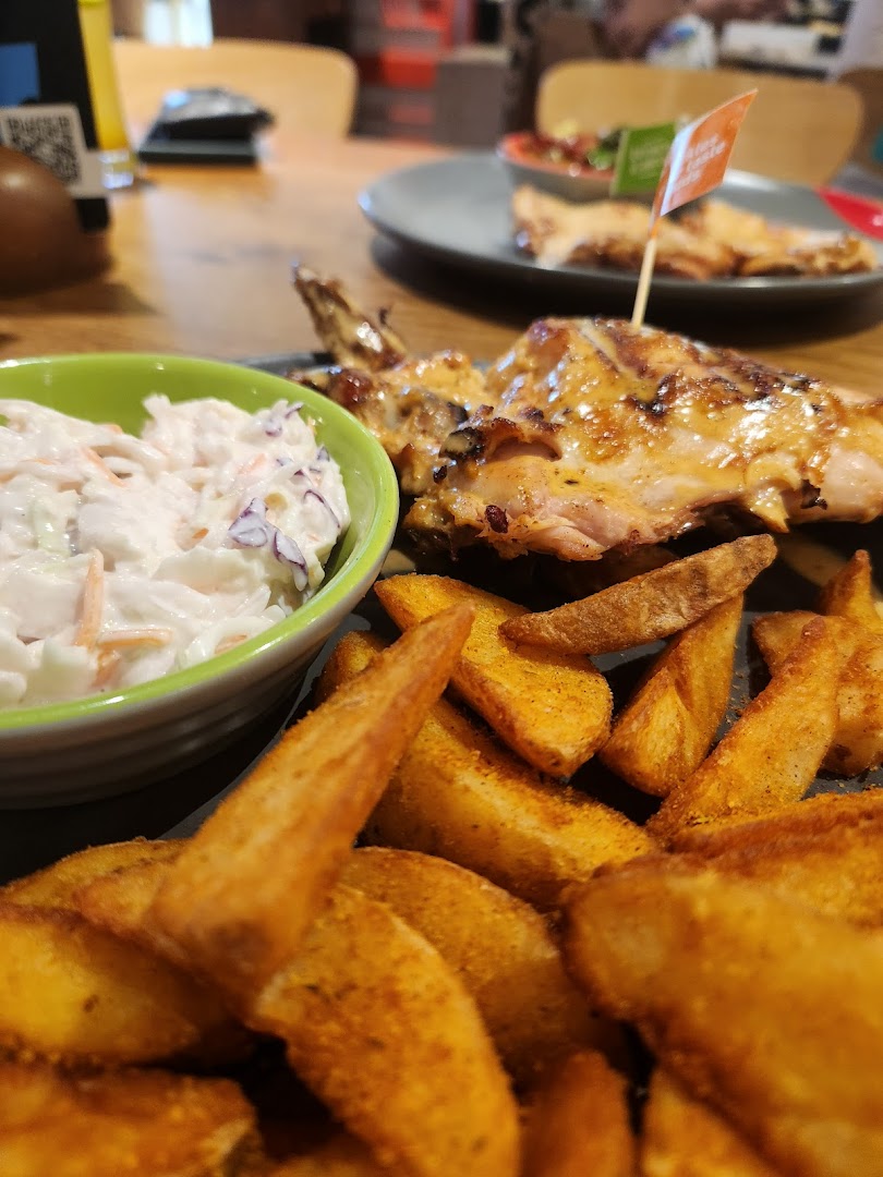 A close-up of Nando's flame-grilled PERi-PERi chicken with coleslaw and potato wedges.