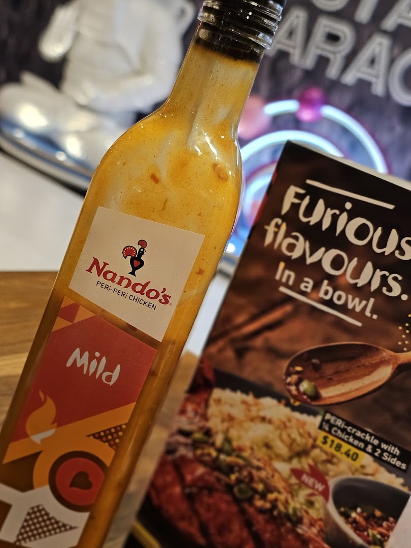A Nando's Mild Peri-Peri sauce bottle next to a promotional flyer for a new PERI-crackle dish.