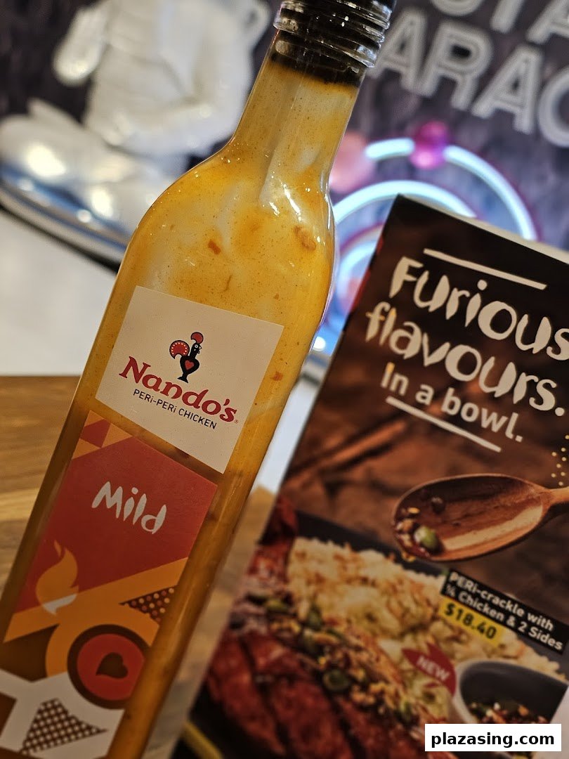 A Nando's Mild Peri-Peri sauce bottle next to a promotional flyer for a new PERI-crackle dish.