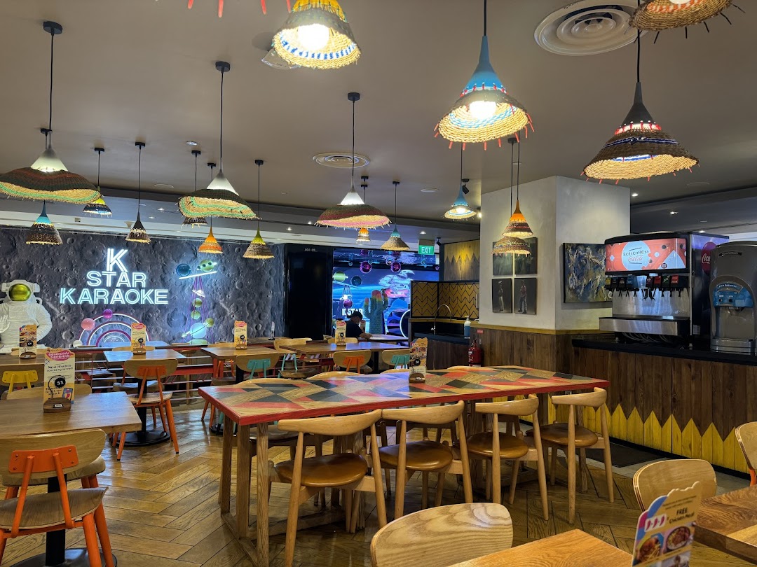 Vibrant interior of Nandos Plaza Singapura, featuring colorful decor, dining tables, and a K Star Karaoke sign.