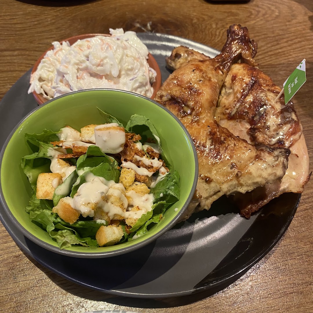 A plate of flame-grilled PERi-PERi chicken with creamy coleslaw and a fresh side salad.