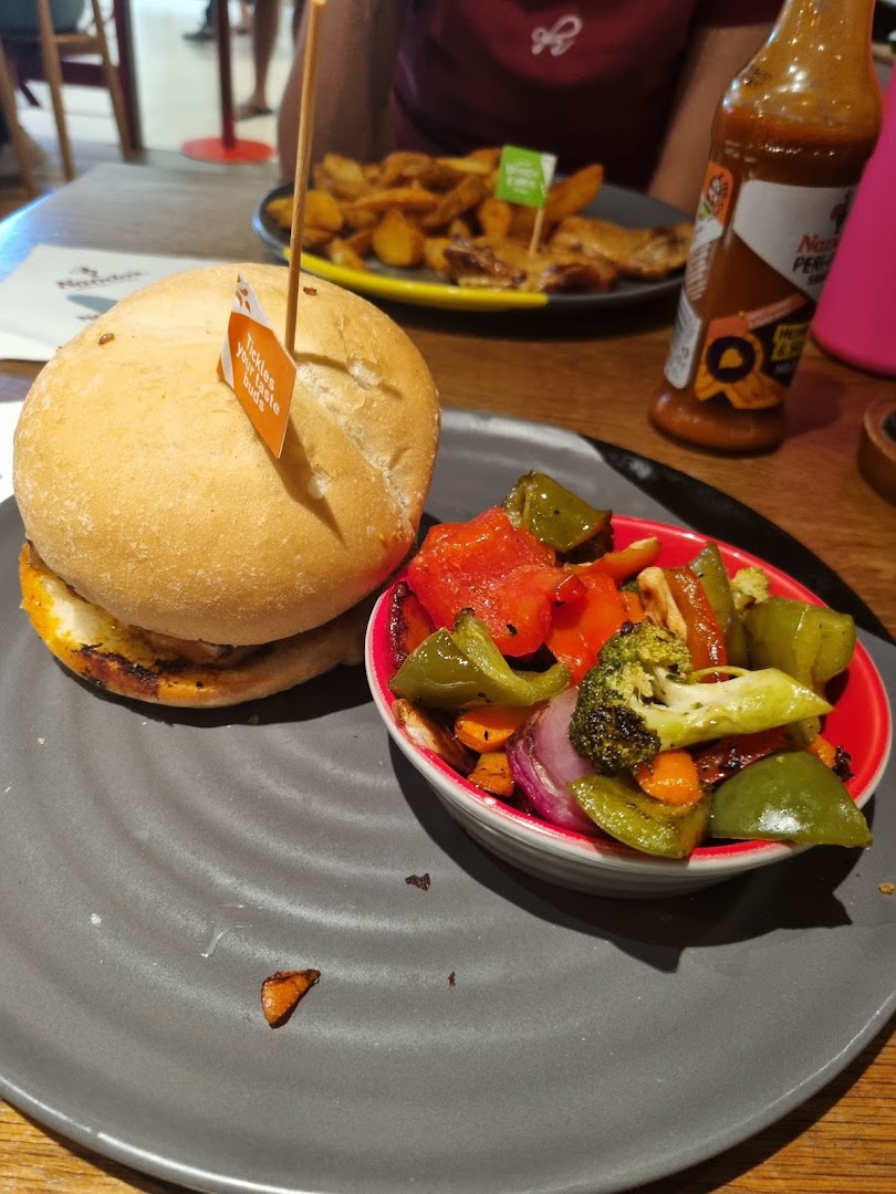 A Nando's burger with roasted vegetables and PERi-PERi sauce, ready to be enjoyed.