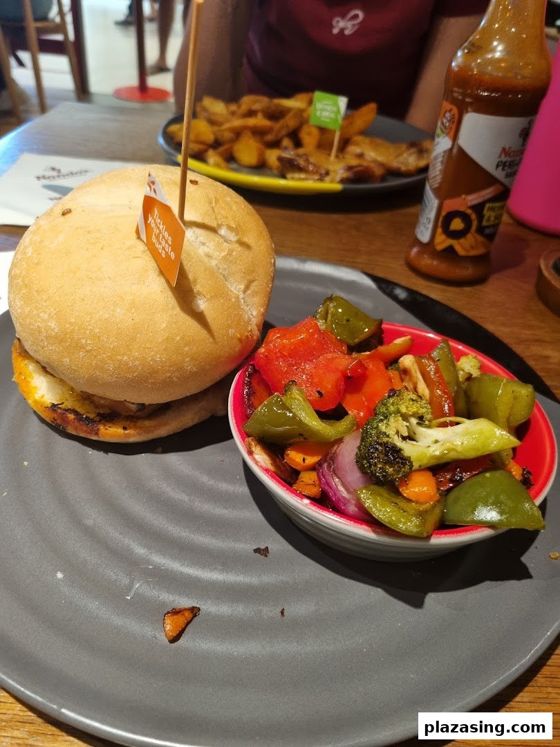 A Nando's burger with roasted vegetables and PERi-PERi sauce, ready to be enjoyed.