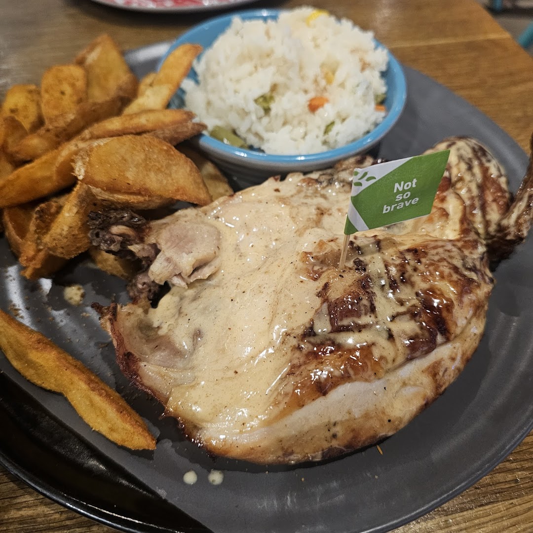 A plate of flame-grilled PERi-PERi chicken with potato wedges and rice.