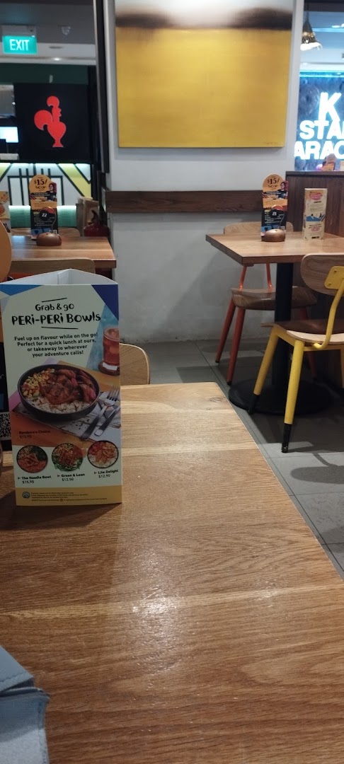 Interior view of Nandos restaurant showing dining tables, chairs, and a menu stand.