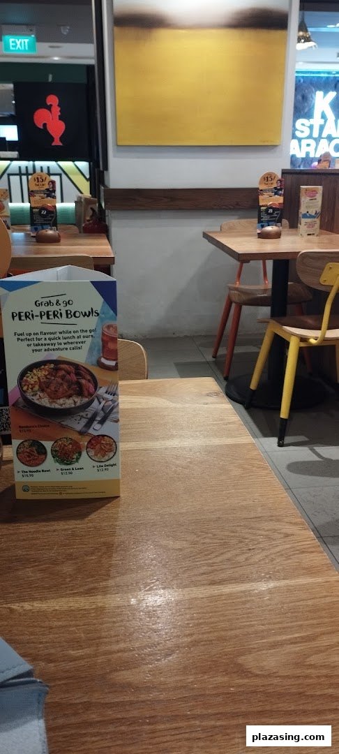 Interior view of Nandos restaurant showing dining tables, chairs, and a menu stand.