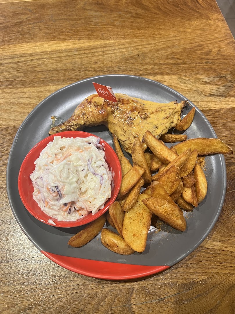 A plate of Nando's flame-grilled PERi-PERi chicken with potato wedges and coleslaw.