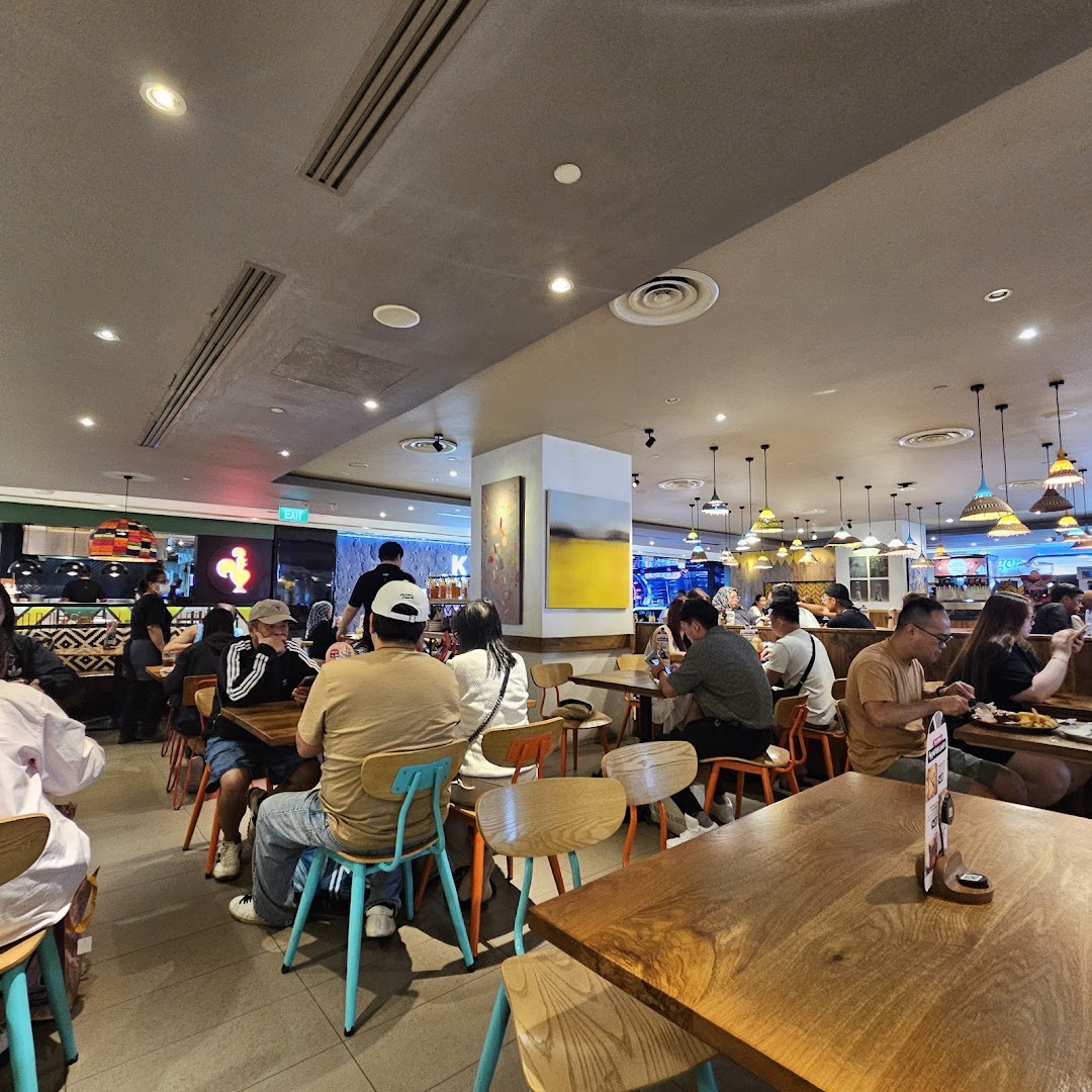 Diners enjoying meals in the vibrant, spacious interior of Nandos restaurant at Plaza Singapura.