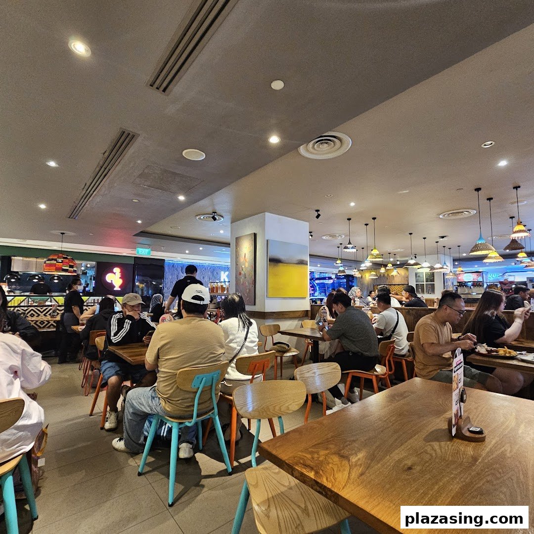 Diners enjoying meals in the vibrant, spacious interior of Nandos restaurant at Plaza Singapura.