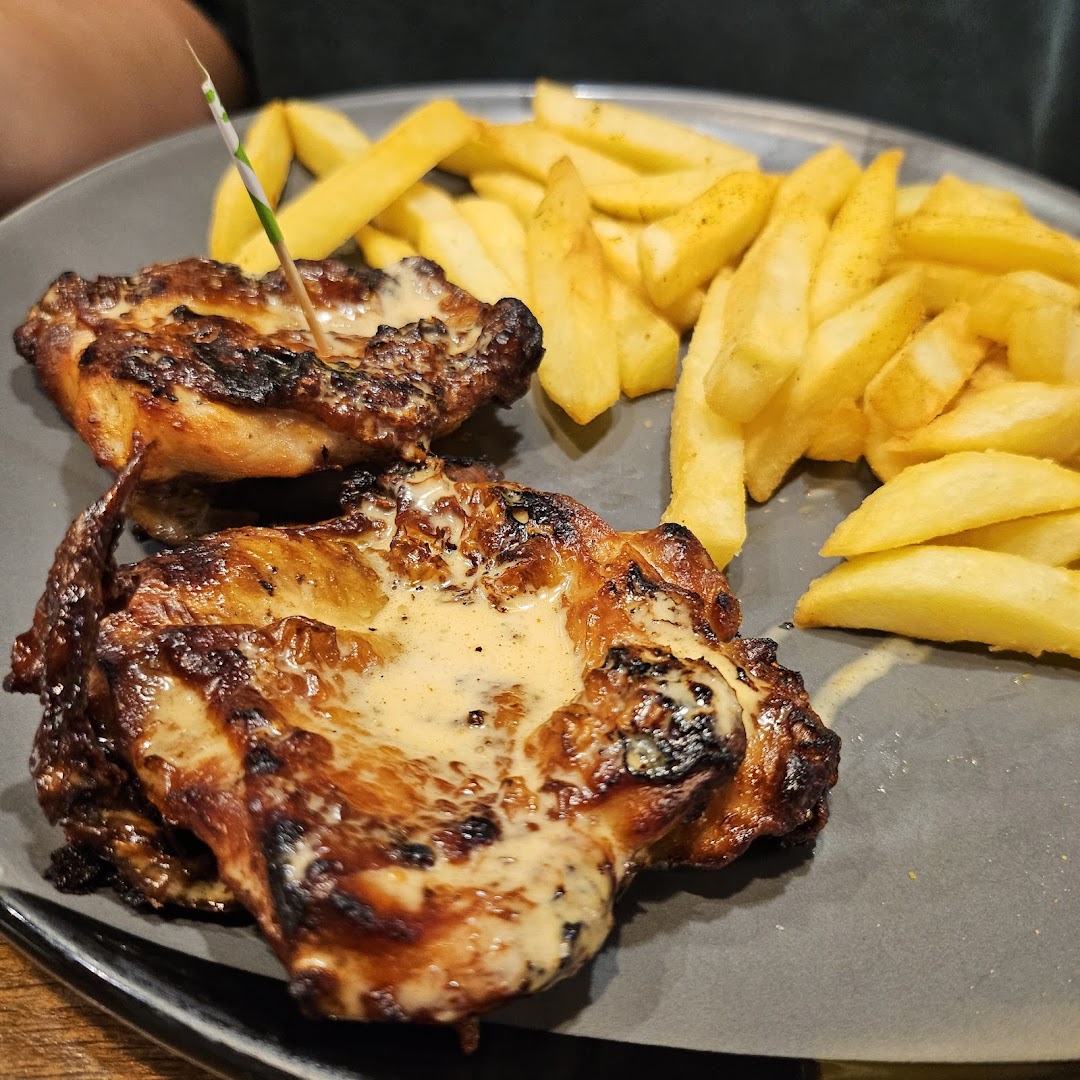 A plate of flame-grilled PERi-PERi chicken with creamy sauce and golden fries.