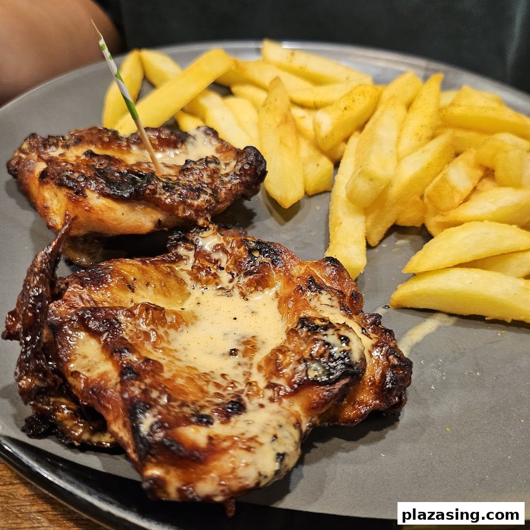 A plate of flame-grilled PERi-PERi chicken with creamy sauce and golden fries.