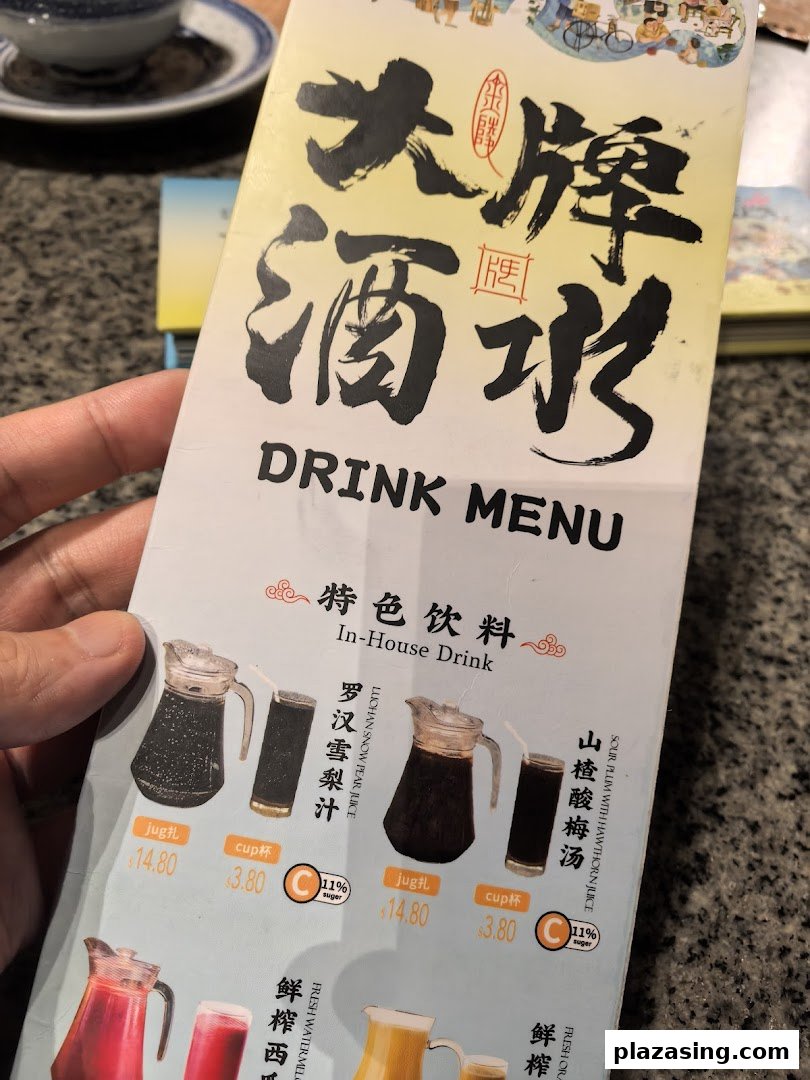 A hand holds open a drink menu displaying traditional Chinese beverages and prices.