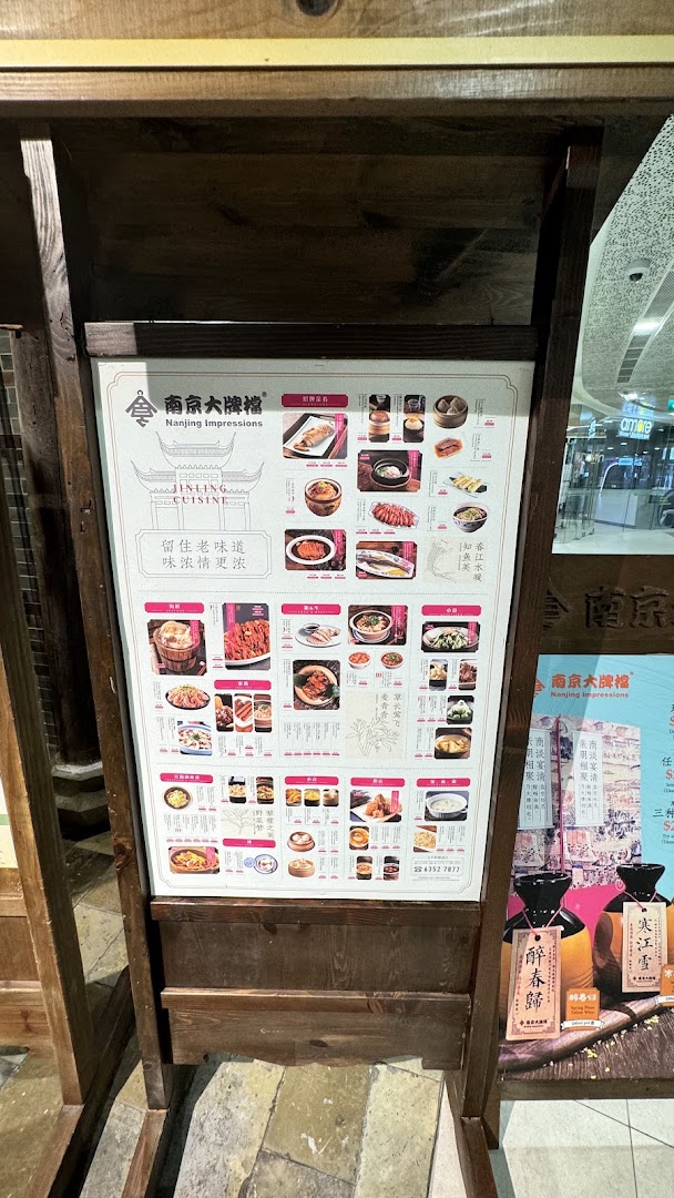 A wooden stand displaying a large promotional menu board for Nanjing Impressions restaurant, featuring various Jinling cuisine dishes.