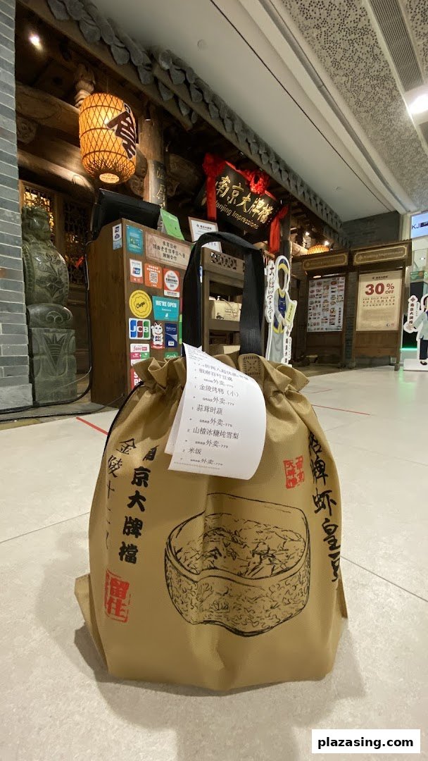 A takeaway bag from Nanjing Impressions restaurant stands before its traditional Chinese entrance.