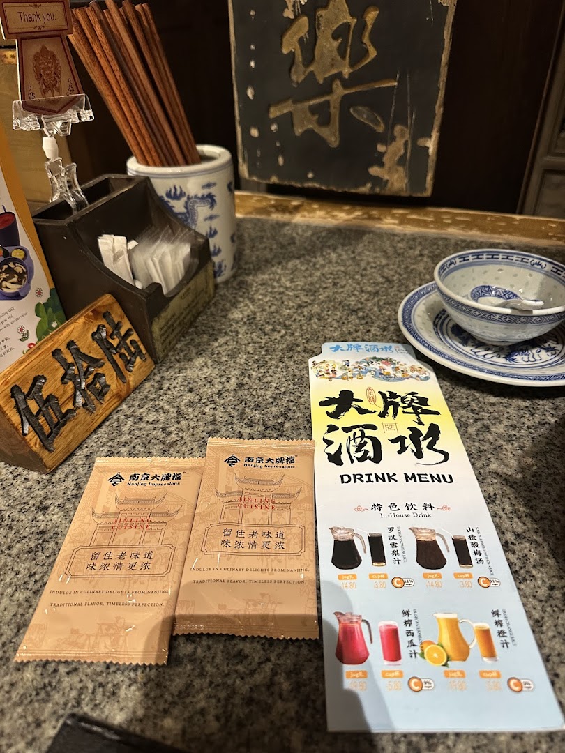 A traditional Chinese restaurant table setting featuring a drink menu, chopsticks, and branded packaging.