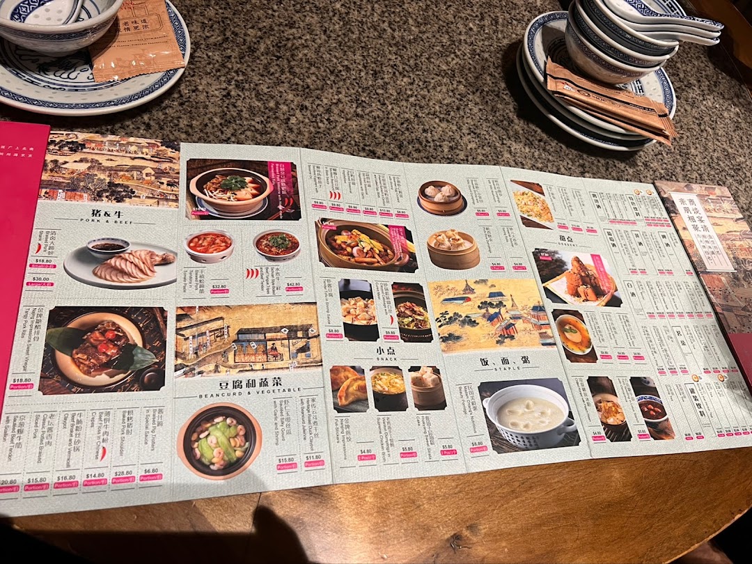An open menu displaying various Chinese dishes with photos and prices, set on a table with tableware.