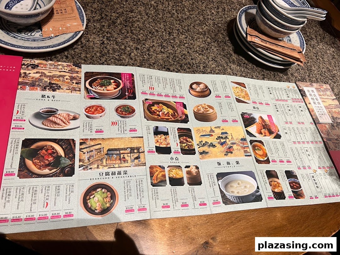 An open menu displaying various Chinese dishes with photos and prices, set on a table with tableware.