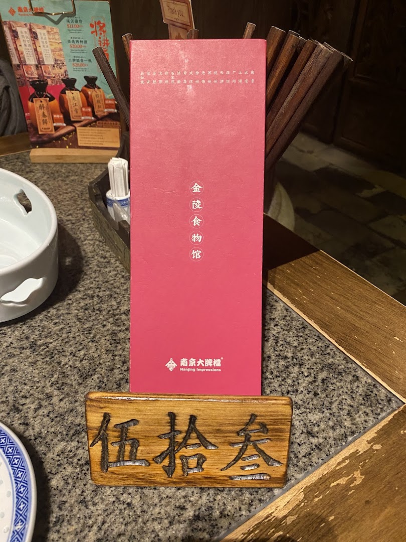 A table setting at Nanjing Impressions, featuring a branded red box and a wooden table number.
