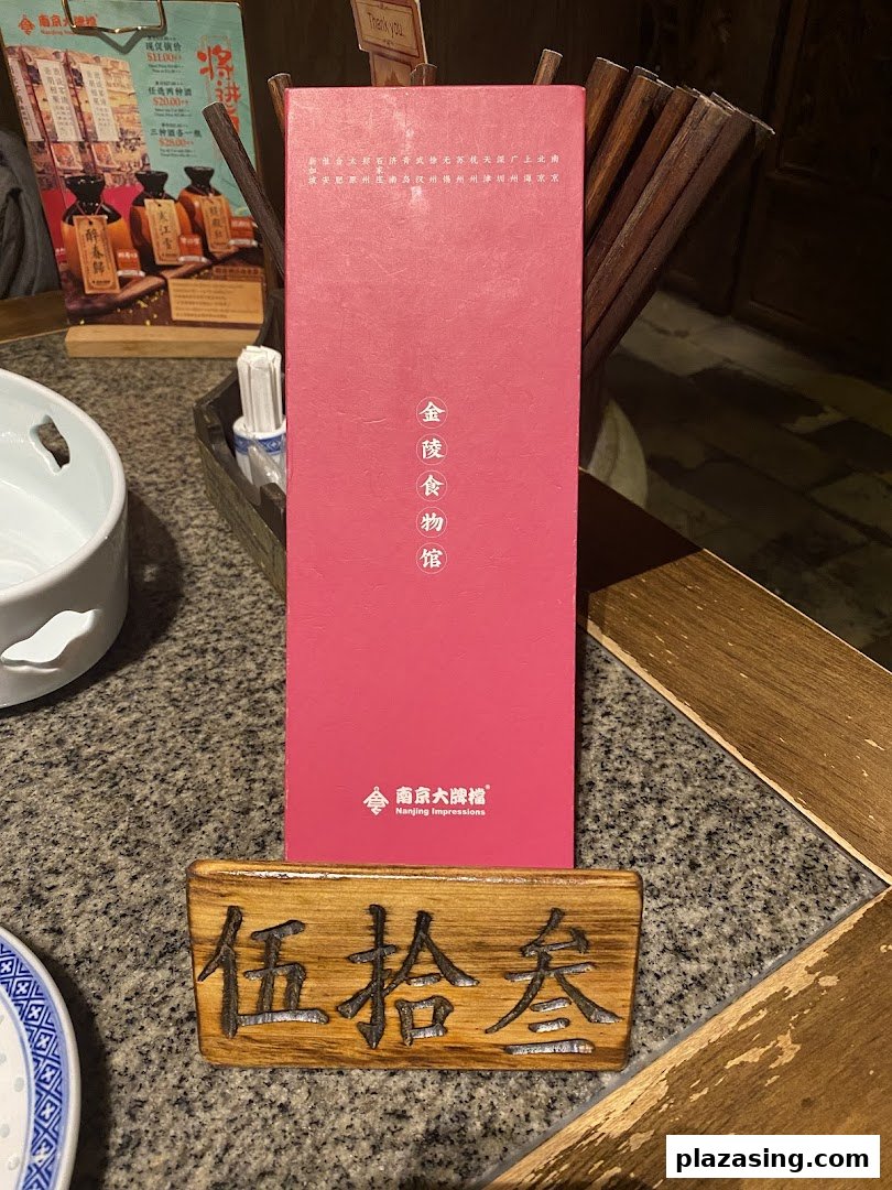 A table setting at Nanjing Impressions, featuring a branded red box and a wooden table number.